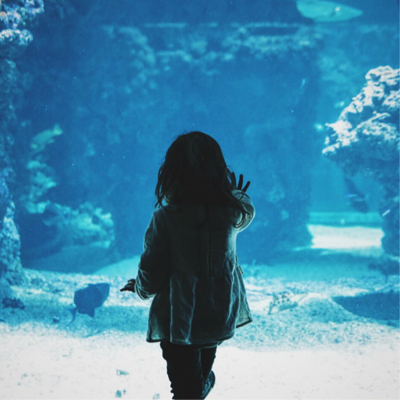 girl standing against aquarium glass